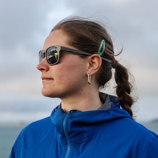 Person wearing a pair of Towan Raw sunglasses with a side profile against a cloudy sky.
