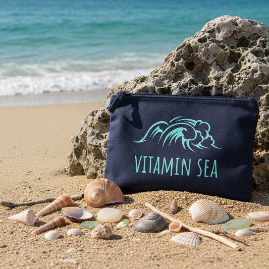 Navy accessory pouch with blue 'Vitamin Sea' design on a beach.