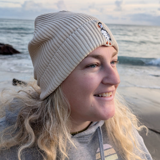 Woman wearing Cream Organic Cotton Puffin Beanie on the beach 