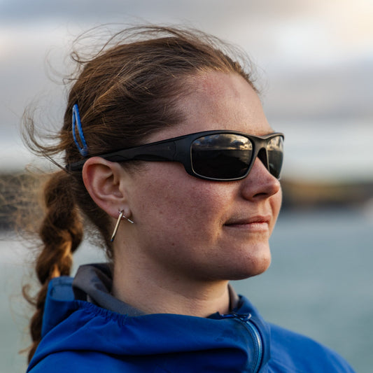 Woman wearing black recycled ocean plastic sunglasses by the sea 