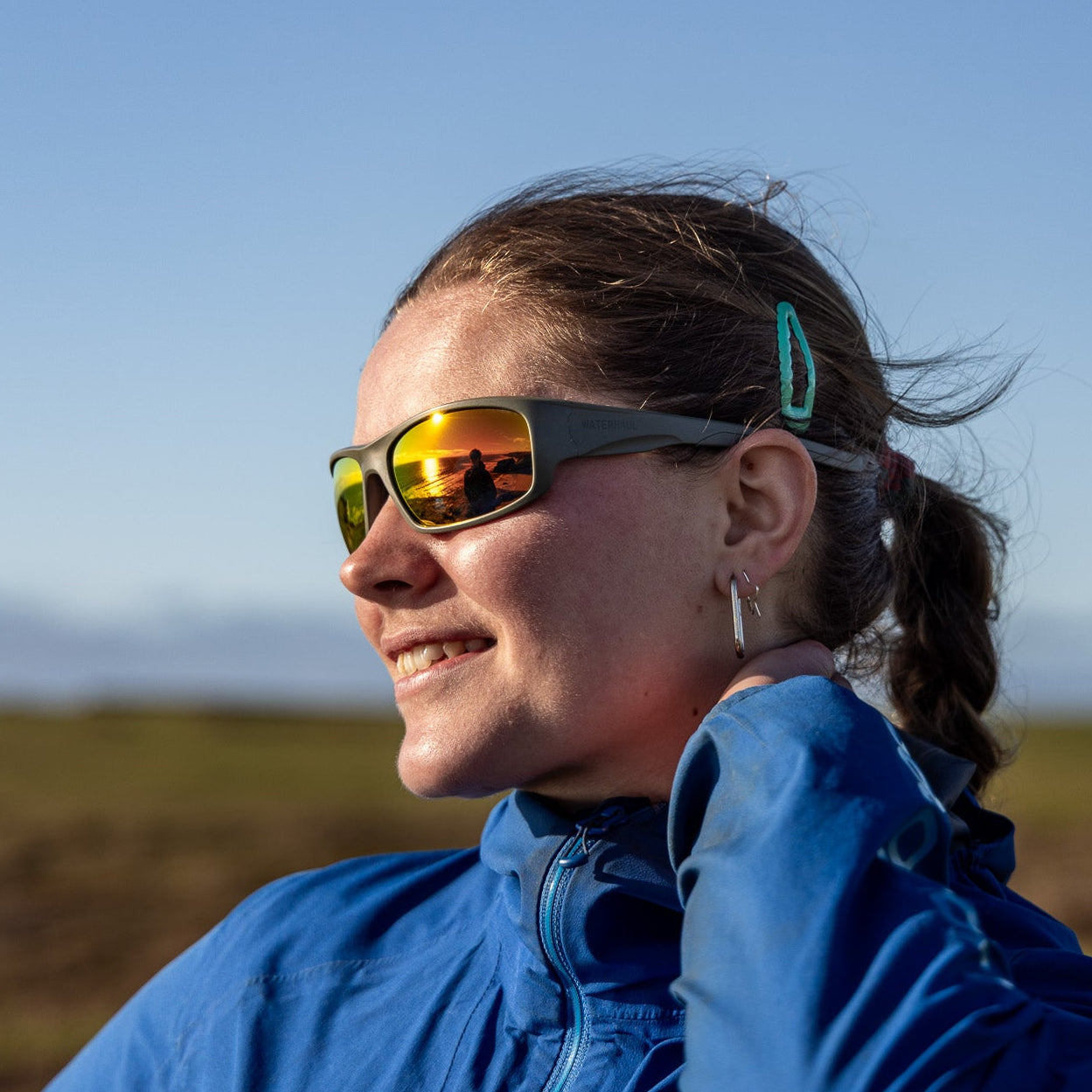 Person wearing Green recycled polarised sunglasses with an orange lens. 
