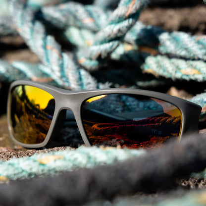 Wrap-around eco-friendly sunglasses with reflective orange mirrored lenses, made from recycled fishing nets recovered from UK beaches. 