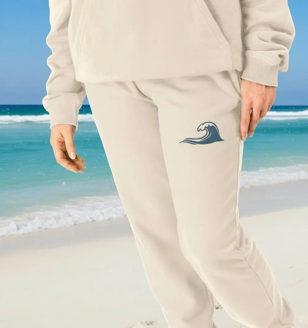 Women staying cozy in Ocean Wave Jogging Bottoms organic cotton fleece joggers in oat colour for hiking and coastal walks