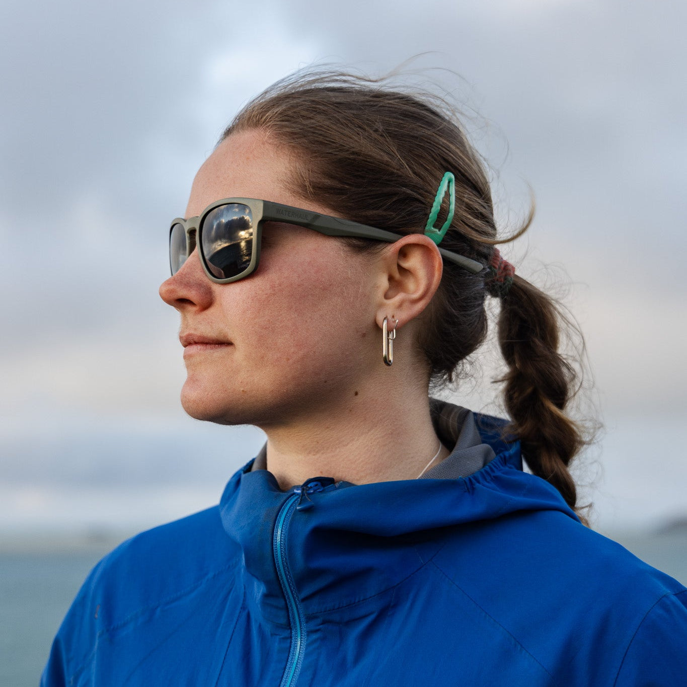 Person wearing a pair of Towan Raw sunglasses with a side profile against a cloudy sky.