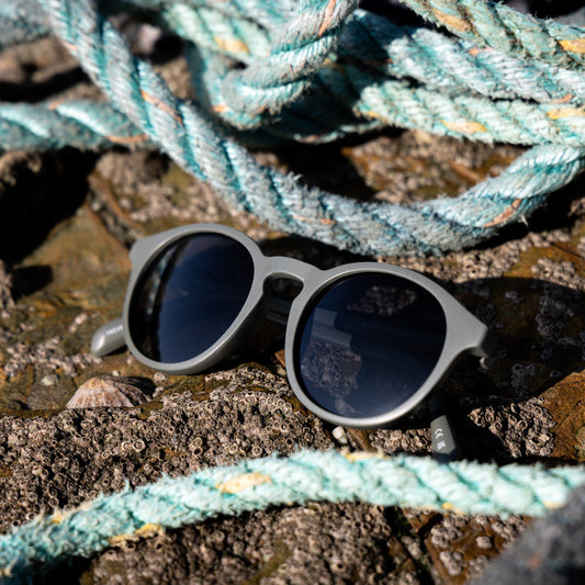 Ghost net sunglasses on a stone surface with fishing ropes in the background