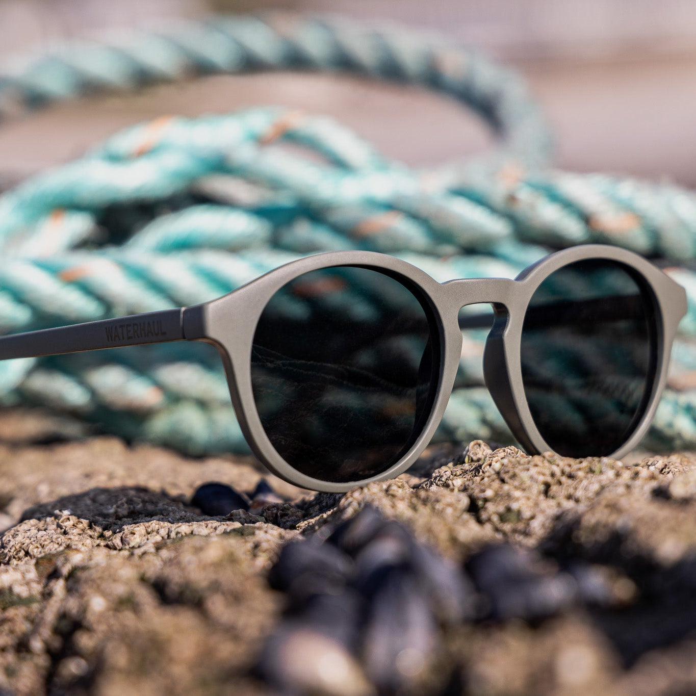 Waterhaul trevellas sunglasses made from ocean plastic on a sandy surface with ropes in the background