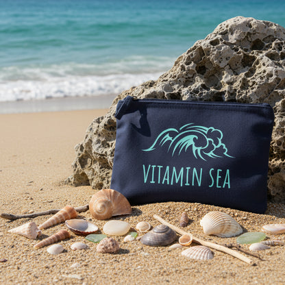 Navy accessory pouch with blue 'Vitamin Sea' design on a beach. 