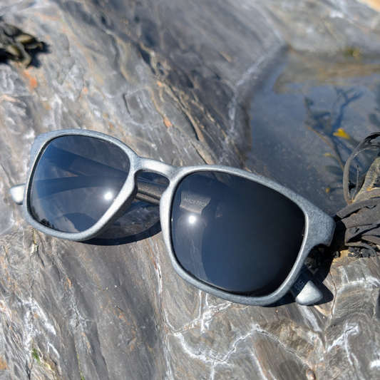 grey recycled ghost net sunglasses on a rocky surface