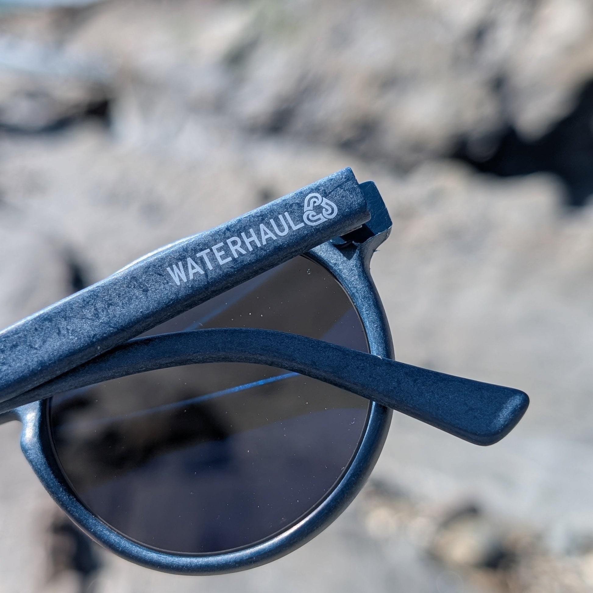 View of back of navy rounded sunglasses by waterhaul showing logo 