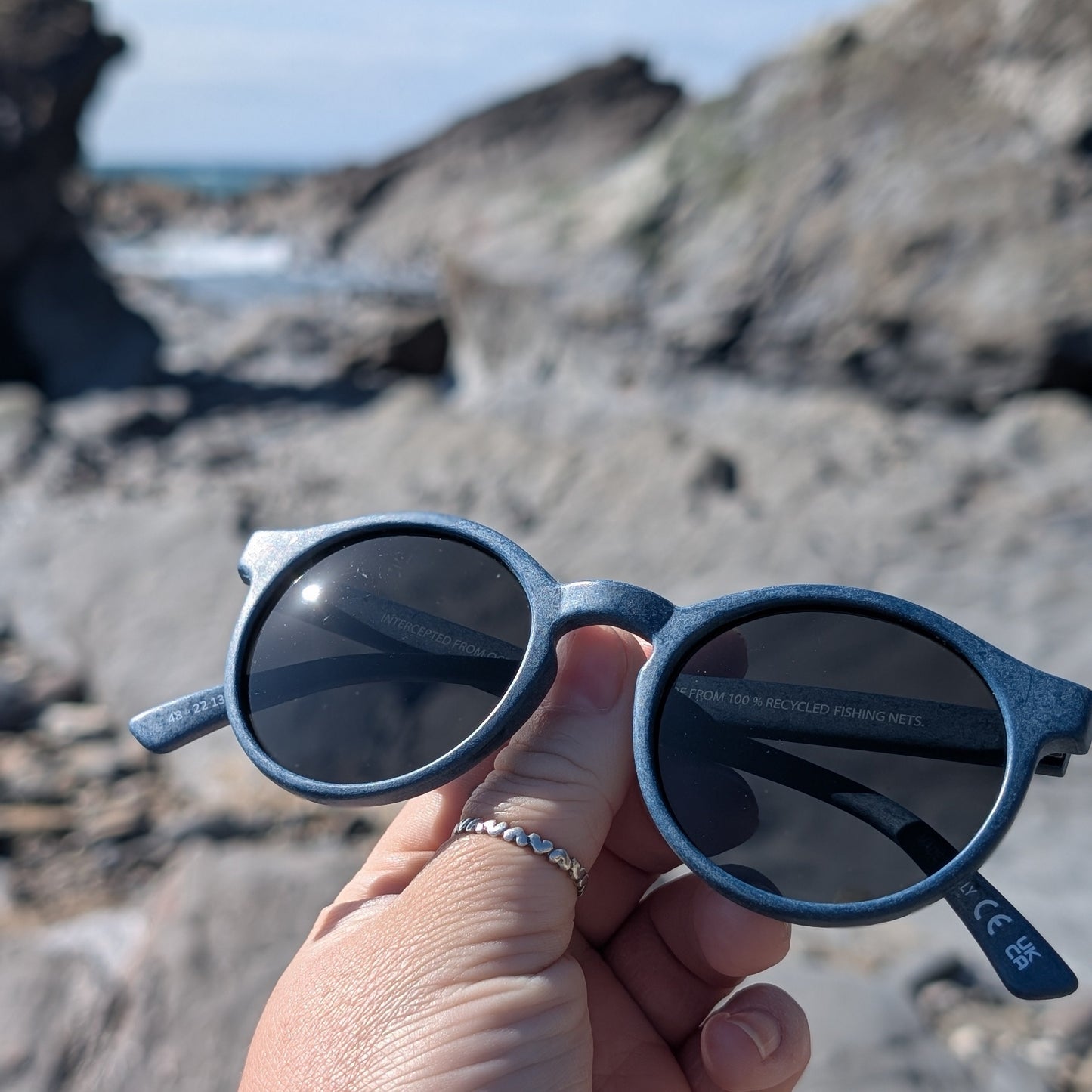 navy panto sunglasses made with recycled ocean plastic on the beach