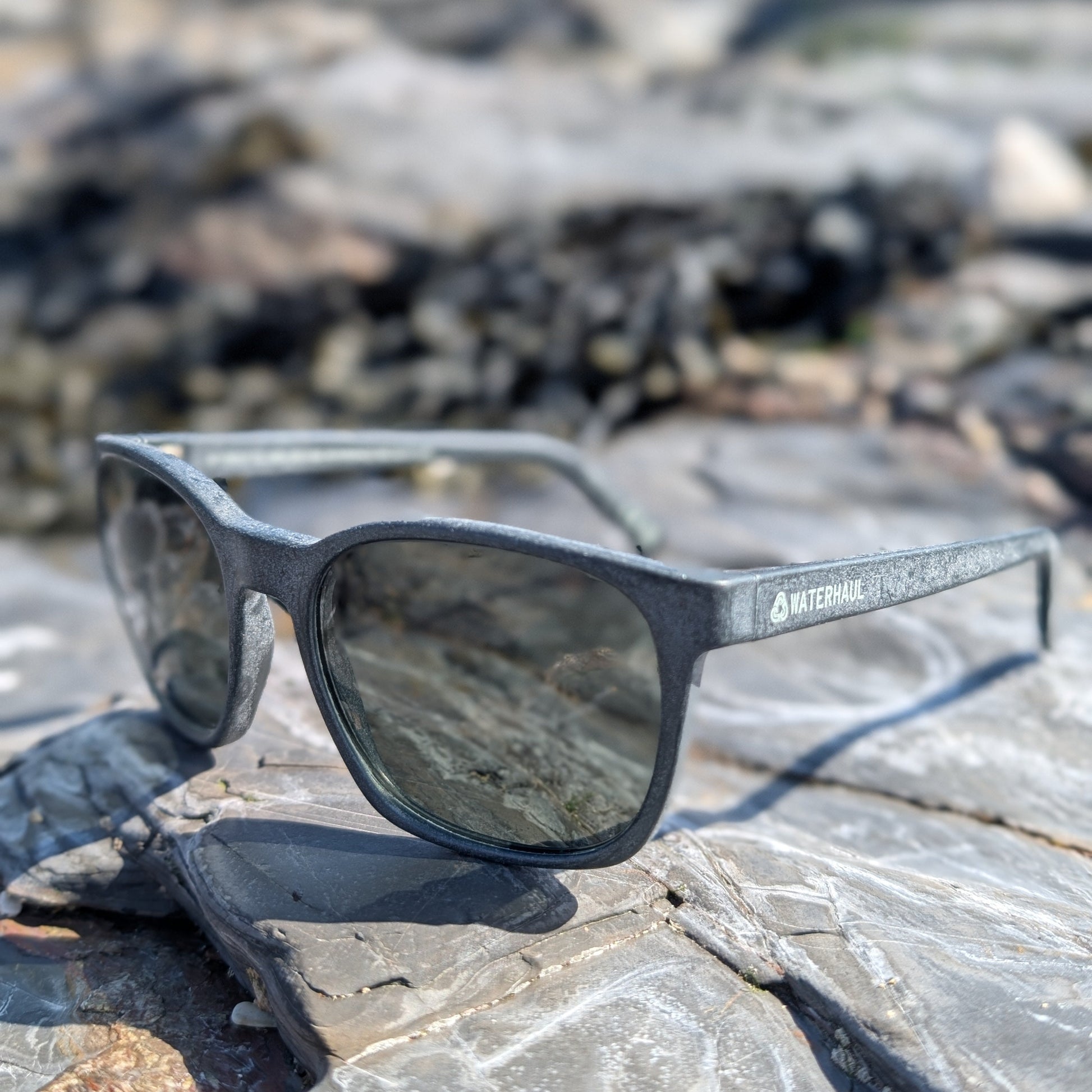 waterhaul recycled ghost net sunglasses sitting on a rock with the logo visible
