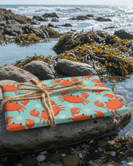 Wrapping paper with a Christmas-themed crab design, orange and blue in color, tied with a string.