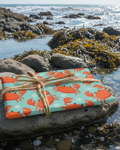 Wrapping paper with a Christmas-themed crab design, orange and blue in color, tied with a string.