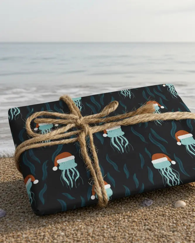 Gift wrapped in blue paper with blue jellyfish wearing santa hats pattern on a beach.