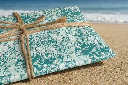 A sheet of wrapping paper with a sea foam design, tied with a string to a cardboard base, representing the product's use for gift wrapping.