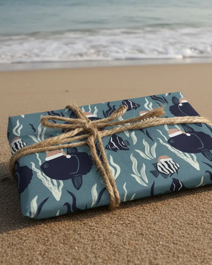 A sheet of eco-friendly wrapping paper with a Christmas-themed design featuring sunfish and other marine life, tied with a string and presented with a natural brown paper background.